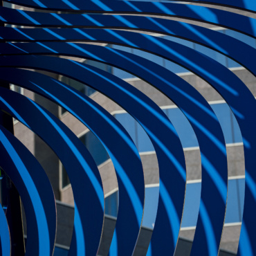 Nova's Rhythm finds transformation in Cecilia Lueza's sculpture on Hogan Street, where sunlight cutting between curved steel ribs turns fixed metal into something closer to dance, arcs that move without moving.